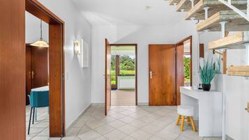 A modern interior with a staircase, a dining area, and a view to the outside.