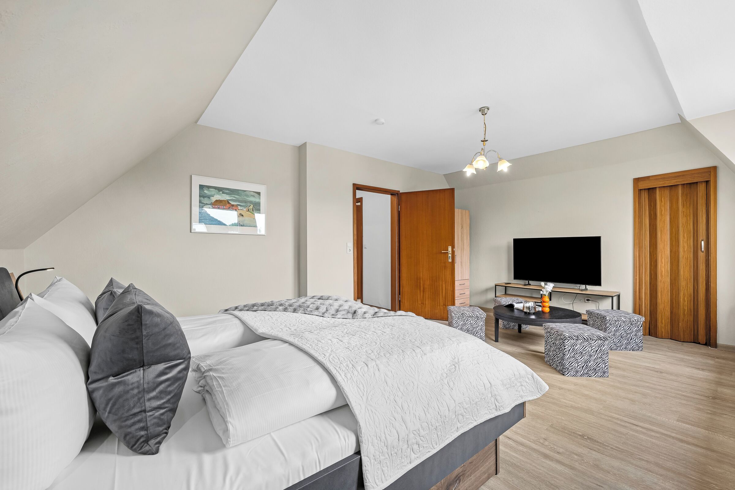 Een slaapkamer met een bed, een televisie, een bureau en een stoel.