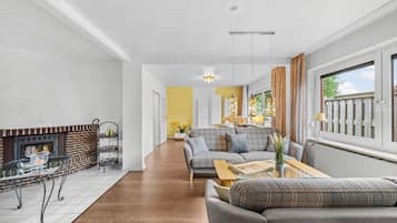 Een moderne woonkamer met een open haard, een zithoek, een salontafel en een eetgedeelte met gele wanden.