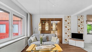 Ett modernt vardagsrum med en soffa, ett soffbord, en tv och ett fönster med utsikt över en röd byggnad.
