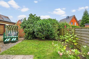 Een tuin met gazon, houten omheining en een groene zitplek.