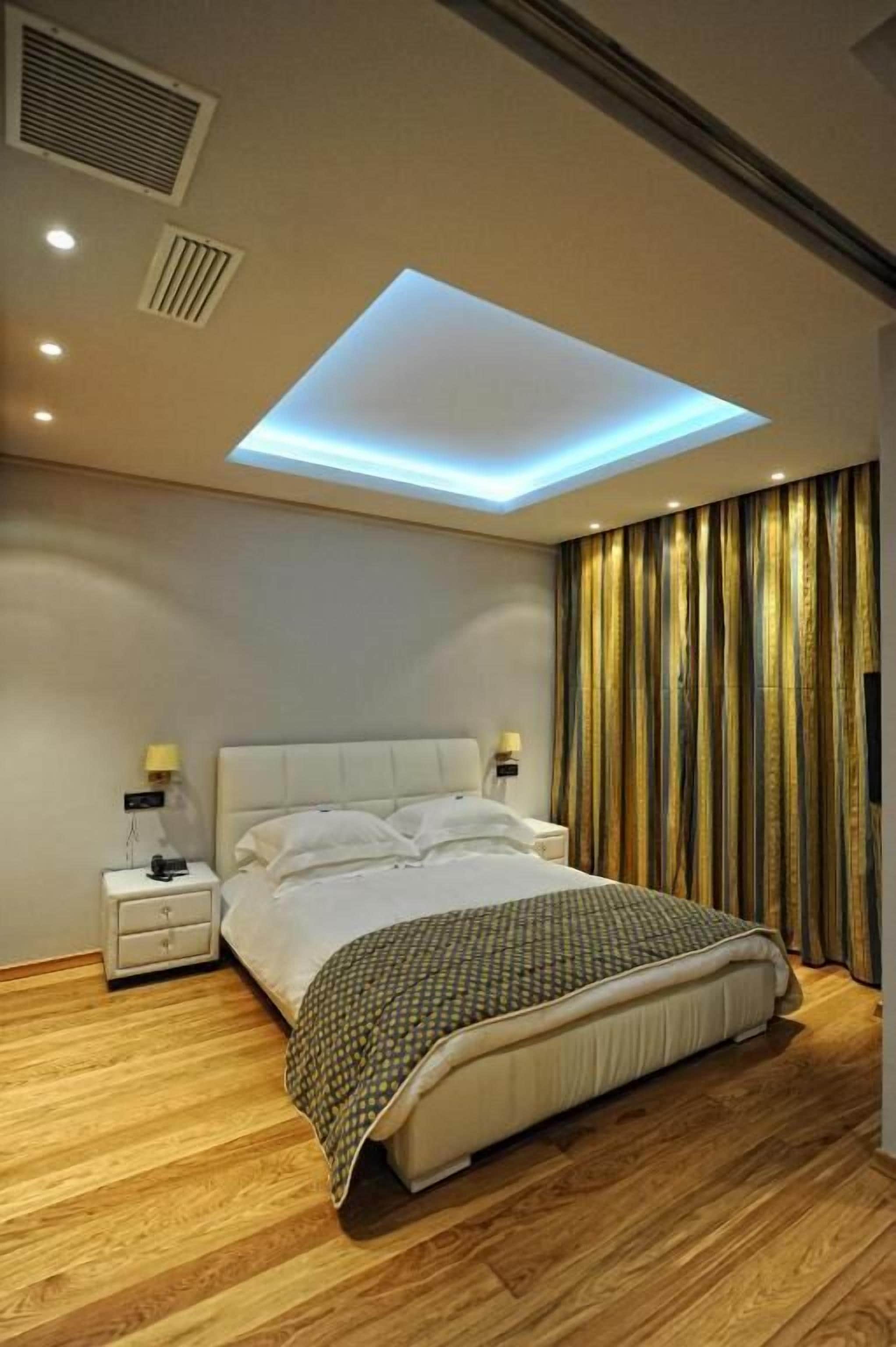 A modern bedroom with a skylight, a bed, bedside tables, and curtains.