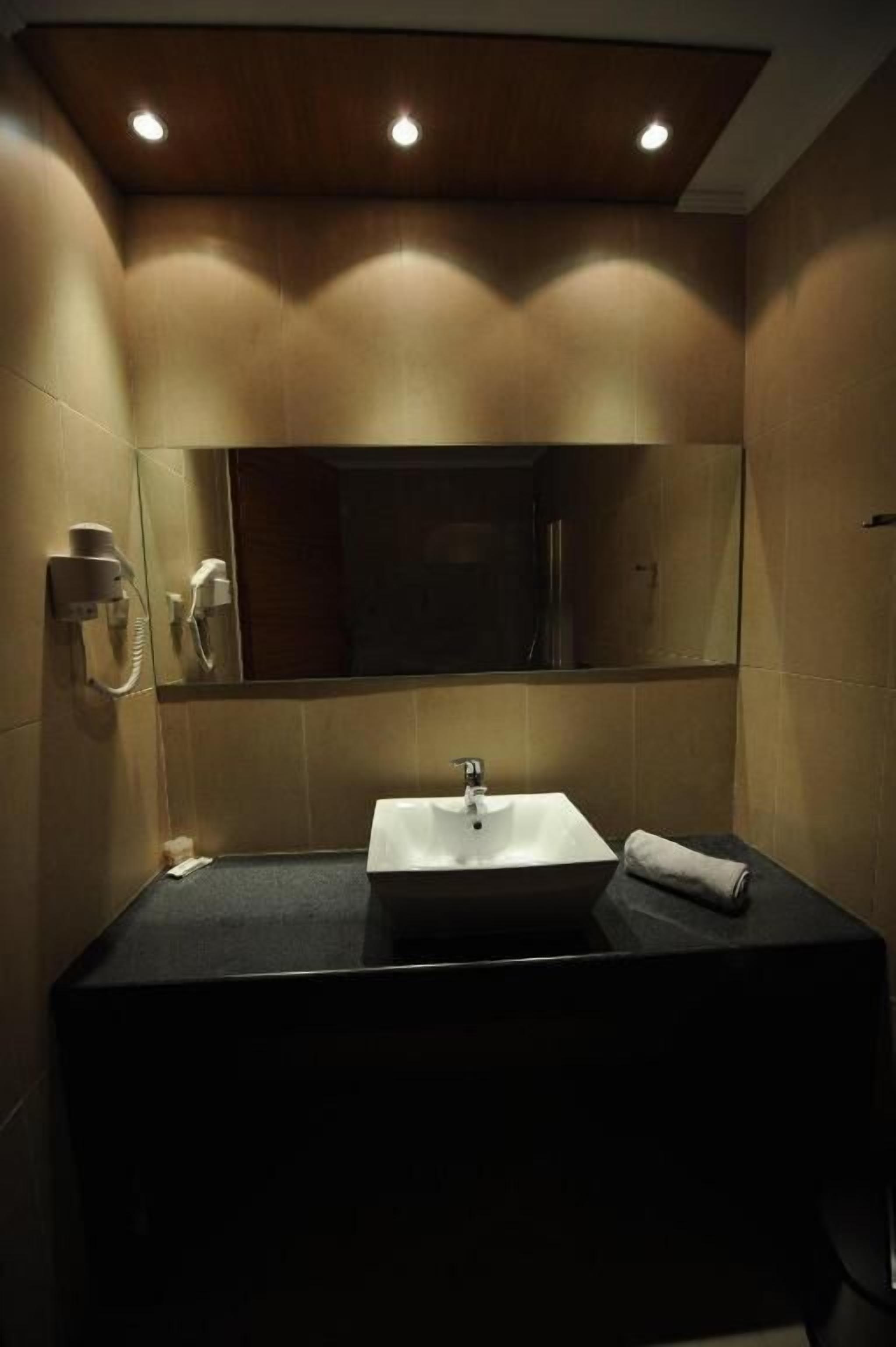 A bathroom with a dark countertop, a white sink, a mirror, and a towel.