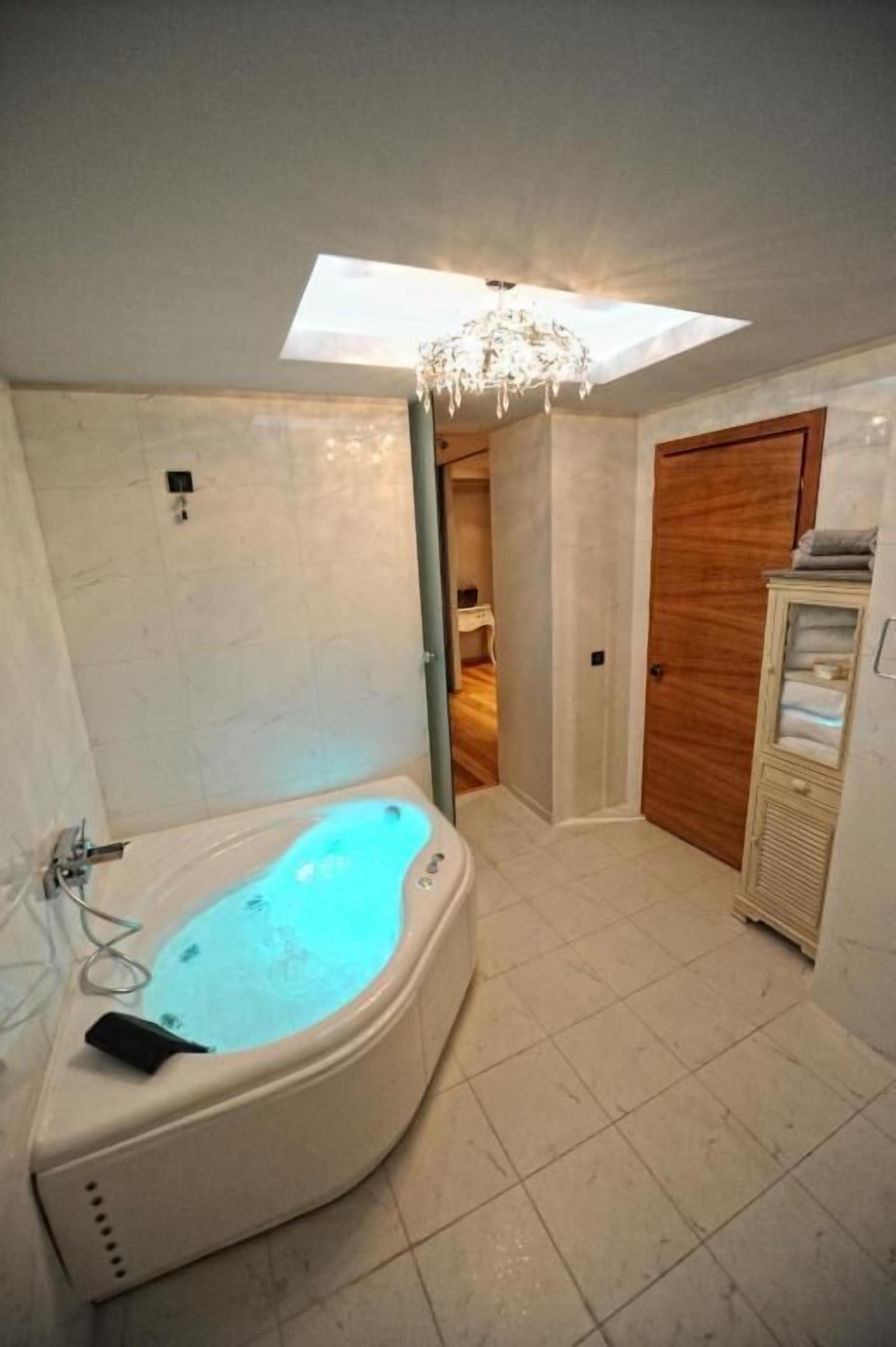A bathroom with a freestanding bathtub, a wooden door, and a ceiling skylight.