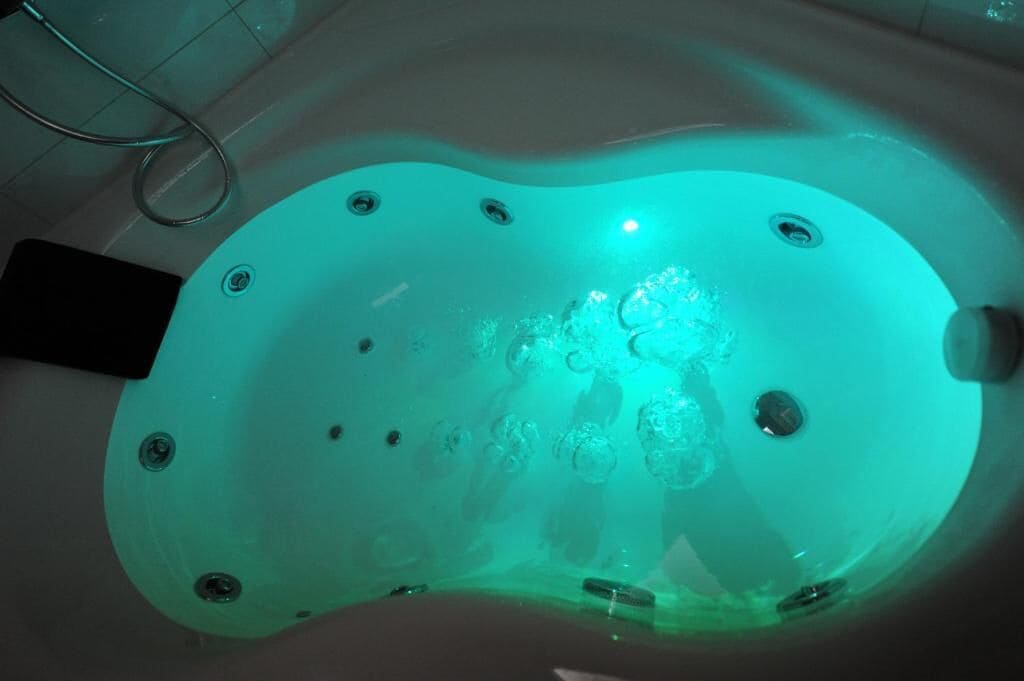 A bathtub with a unique shape and multiple faucets.
