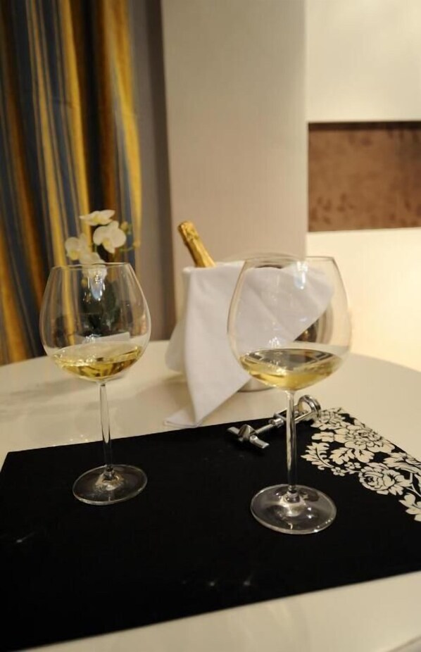 Two glasses of white wine on a table with a black cloth and a bottle of champagne.