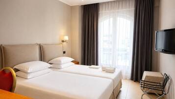 Habitación de hotel con dos camas, televisión, escritorio y una silla.