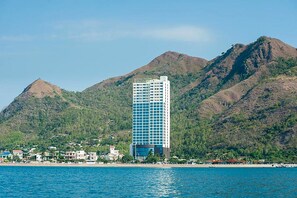 Ein hoch aufragendes Hotel mit moderner Glasfassade, gelegen am Wasser mit Bergen im Hintergrund.