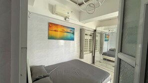 Ein Schlafzimmer mit Bett, einem Gemälde, einem Fenster mit Vorhängen und einem Spiegel.