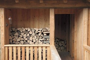 A wooden cabin with a stack of firewood in the foreground and a door leading to another room. - ROMANTIKHÜTTE ROTHAARSTEIG – An idyllic chalet with panoramic views – accommodates up to 8 people (Schmallenberg)