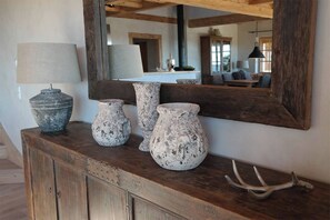 A rustic wooden console with three pottery pieces and a lamp. A mirror reflects the room. - ROMANTIKHÜTTE ROTHAARSTEIG – An idyllic chalet with panoramic views – accommodates up to 8 people (Schmallenberg)