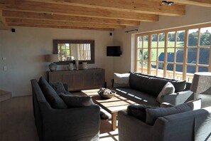 A living room with a sofa set, a coffee table, and a TV mounted on the wall. - ROMANTIKHÜTTE ROTHAARSTEIG – An idyllic chalet with panoramic views – accommodates up to 8 people (Schmallenberg)
