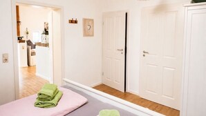 A hotel room with a bed, a mirror, a door, and a hallway leading to another room. - Lütt-Huus — for you & your four-legged friend (Blomberg)