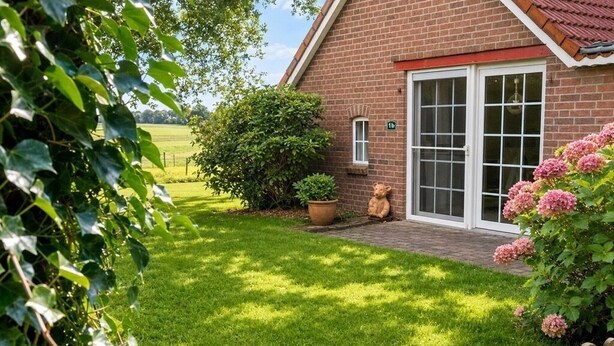 A brick house with a red roof, a front door, and a small garden with a wooden fence. - Lütt-Huus — for you & your four-legged friend (Blomberg)