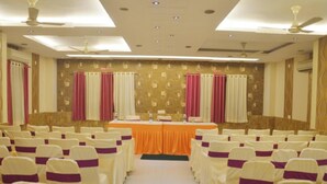 A conference room with rows of chairs, a table, and a ceiling fan. - Muzzafarpur Inn Shivam on Motijheel Rd. (Muzaffarpur)