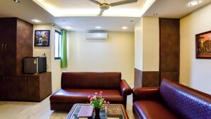 A living room with a ceiling fan, a sofa, a coffee table with a vase, and a television. - Muzzafarpur Inn Shivam on Motijheel Rd. (Muzaffarpur)