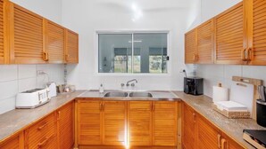 A modern kitchen with wooden cabinets, a large window, and a built-in sink. - The big catch! - 3.5 acres - pets! - boats - fishing and crabbing! (Rodds Bay)