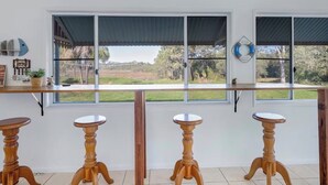 A kitchen with a large window, wooden stools, and a view of the outdoors. - The big catch! - 3.5 acres - pets! - boats - fishing and crabbing! (Rodds Bay)