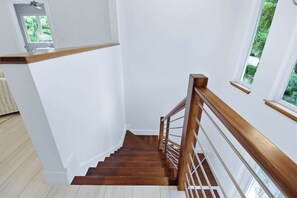 Eine Holztreppe mit weißer Geländer und Blick auf grüne Vegetation.