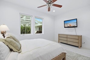 A bedroom with a bed, a dresser, a television, and two windows. - Pine Sanibel - Where Beachfront Living Meets a Boater’s Paradise (Sanibel)