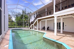 A swimming pool with a glass ceiling, a covered patio area, and a staircase leading to an upper level. - Pine Sanibel - Where Beachfront Living Meets a Boater’s Paradise (Sanibel)