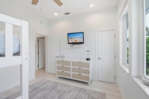 Ein modernes Interieur mit einem an der Wand montierten Fernseher, einem weißen Konsolentisch und einer Tür zu einem weiteren Raum.