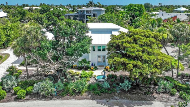 Propiedad residencial con una casa blanca, rodeada de abundante vegetación y una piscina.