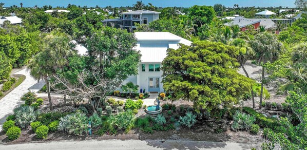 Ein Wohnhaus mit weißen Fassade, umgeben von üppiger Vegetation und einem Swimmingpool.