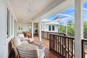 A covered outdoor deck with seating, a barbecue area, and a view of the surrounding landscape. - Pine Sanibel - Where Beachfront Living Meets a Boater’s Paradise (Sanibel)