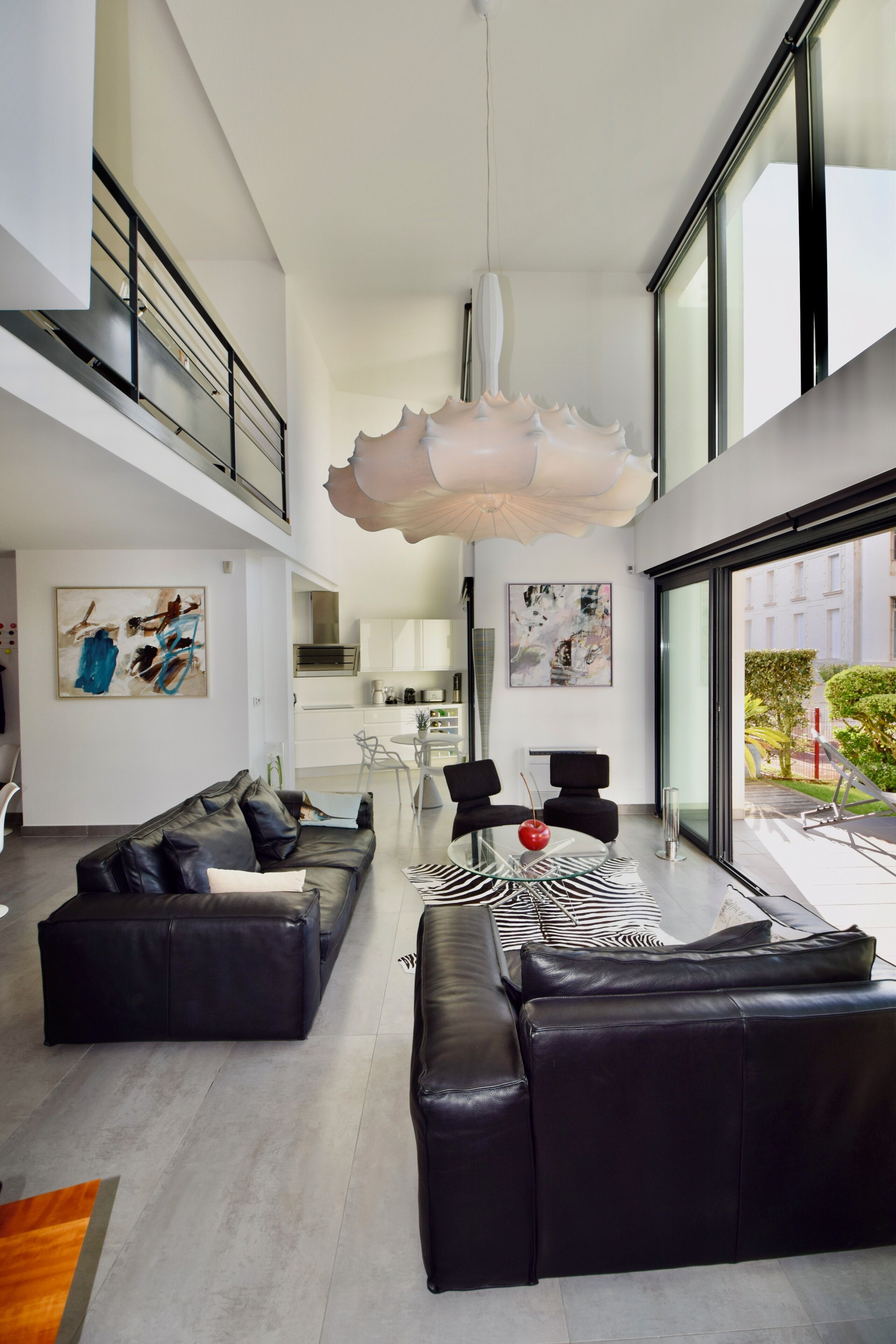 A modern living room with a large black leather sofa, a glass coffee table, and a zebra-patterned rug.