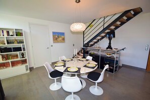 A dining area with a round table, white chairs, and a chandelier. - PRESTIGE RANGE - VACATION RENTALS IN ROYAN AND PONTAILLAC - 2-BEDROOM APARTMENT (Royan)