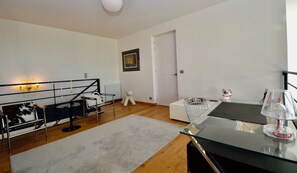 A modern living space with a glass coffee table, a white sofa, a black and white patterned chair, and a small bear figurine. - PRESTIGE RANGE - VACATION RENTALS IN ROYAN AND PONTAILLAC - 2-BEDROOM APARTMENT (Royan)