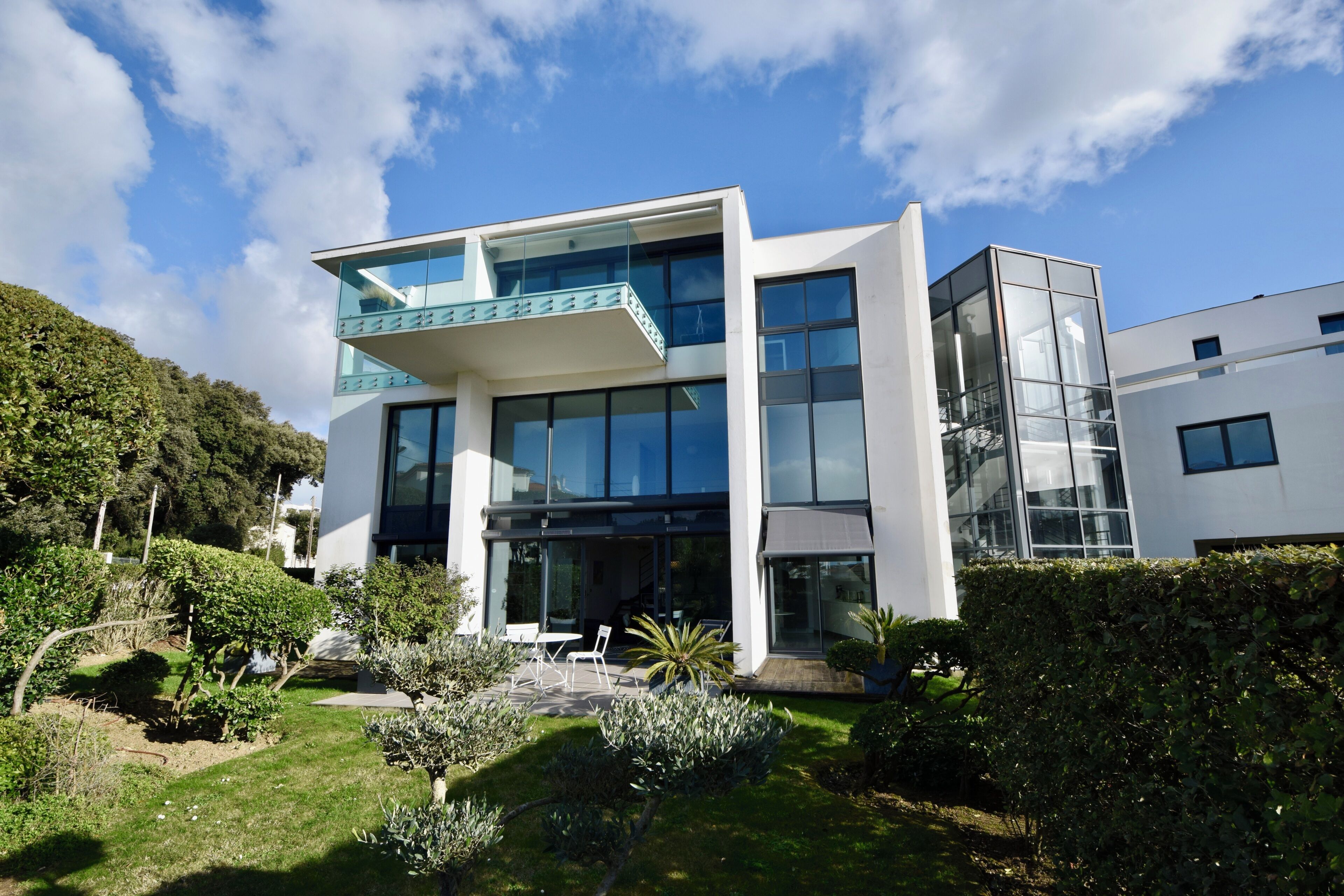 A modern two-story building with large windows and a glass balcony.