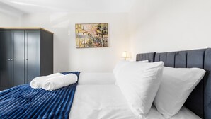 Habitación de hotel con cama, un cuadro, armario y lámpara de noche.