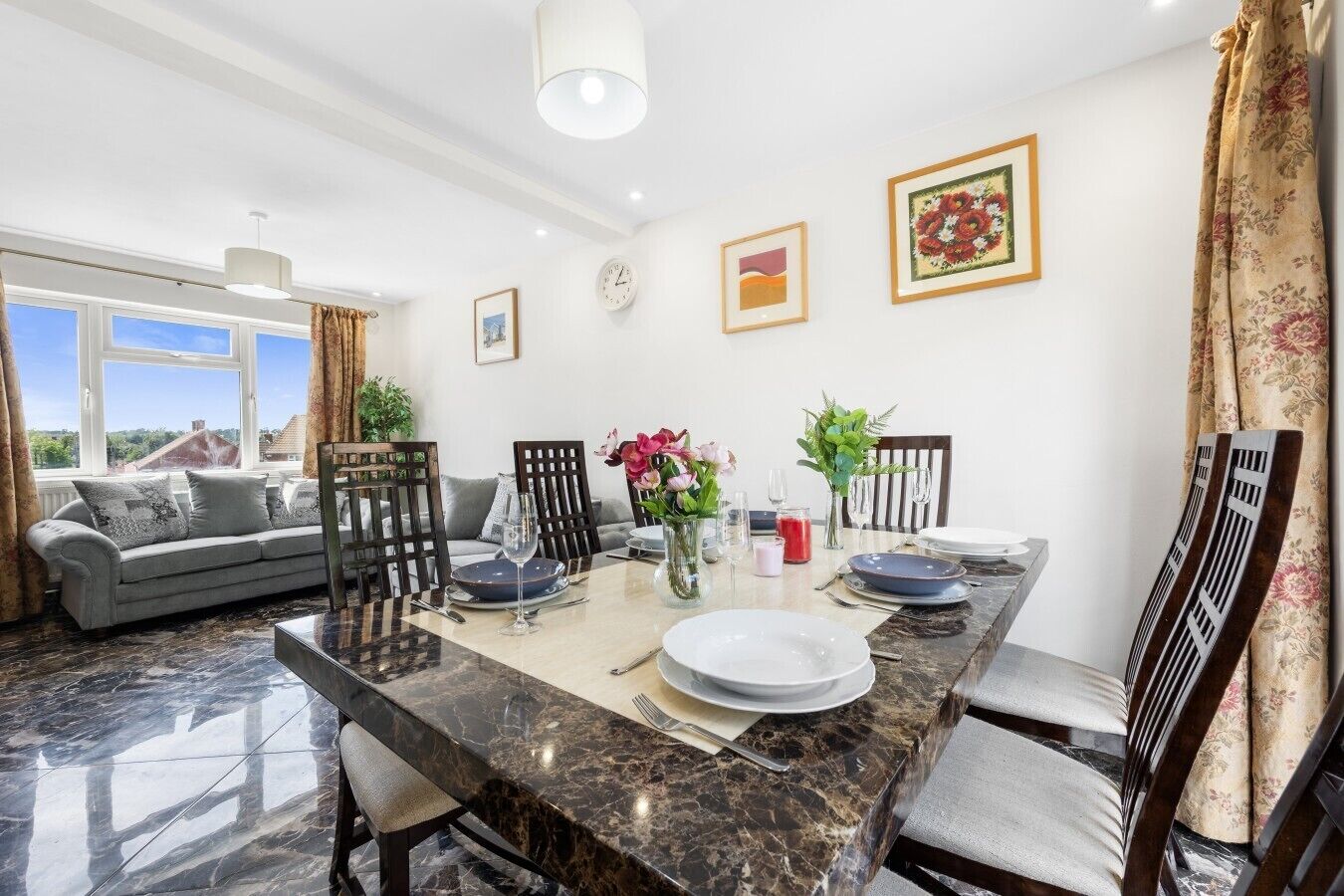 A dining area with a marble table, chairs, and a view of the outdoors.
