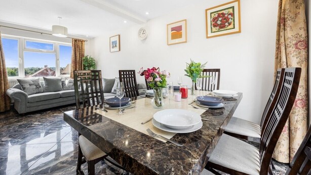 Un comedor con una mesa de mármol, sillas y vistas al exterior.