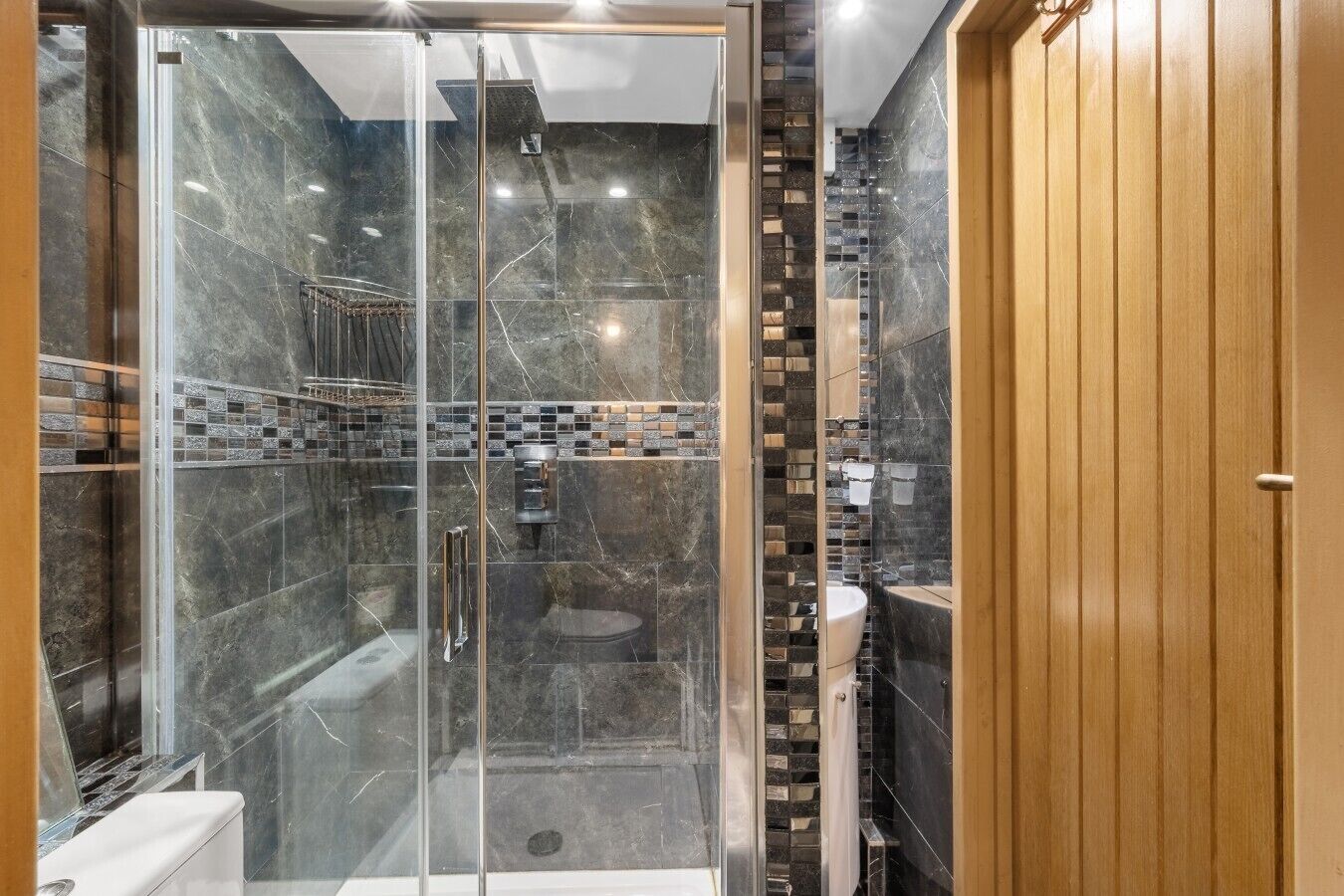 A modern bathroom with a glass-enclosed shower, a toilet, and a sink.