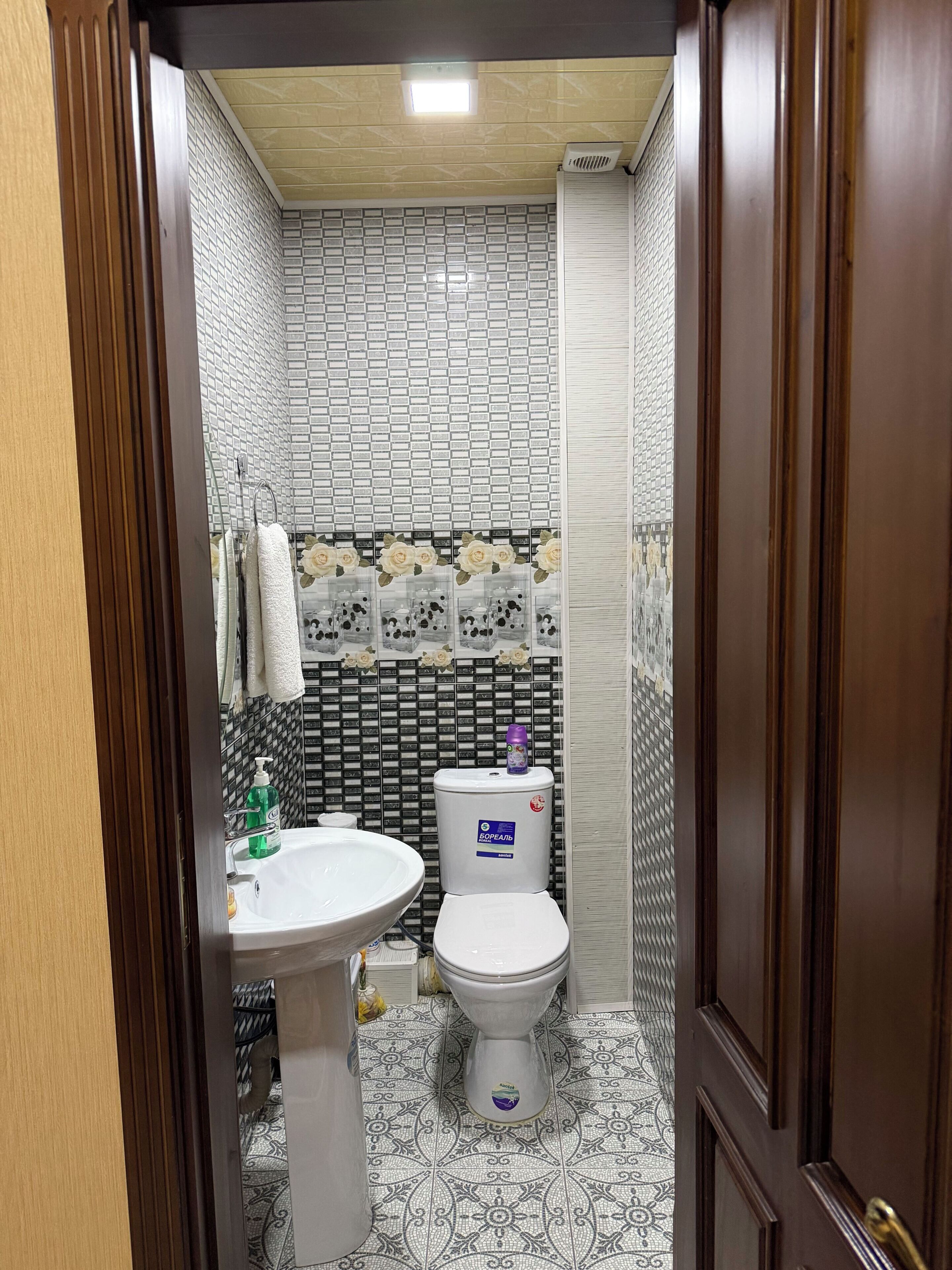Un baño con un lavamanos blanco, un inodoro y un suelo estampado.
