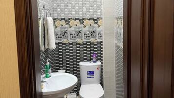 Un baño con un lavamanos blanco, un inodoro y un suelo estampado.