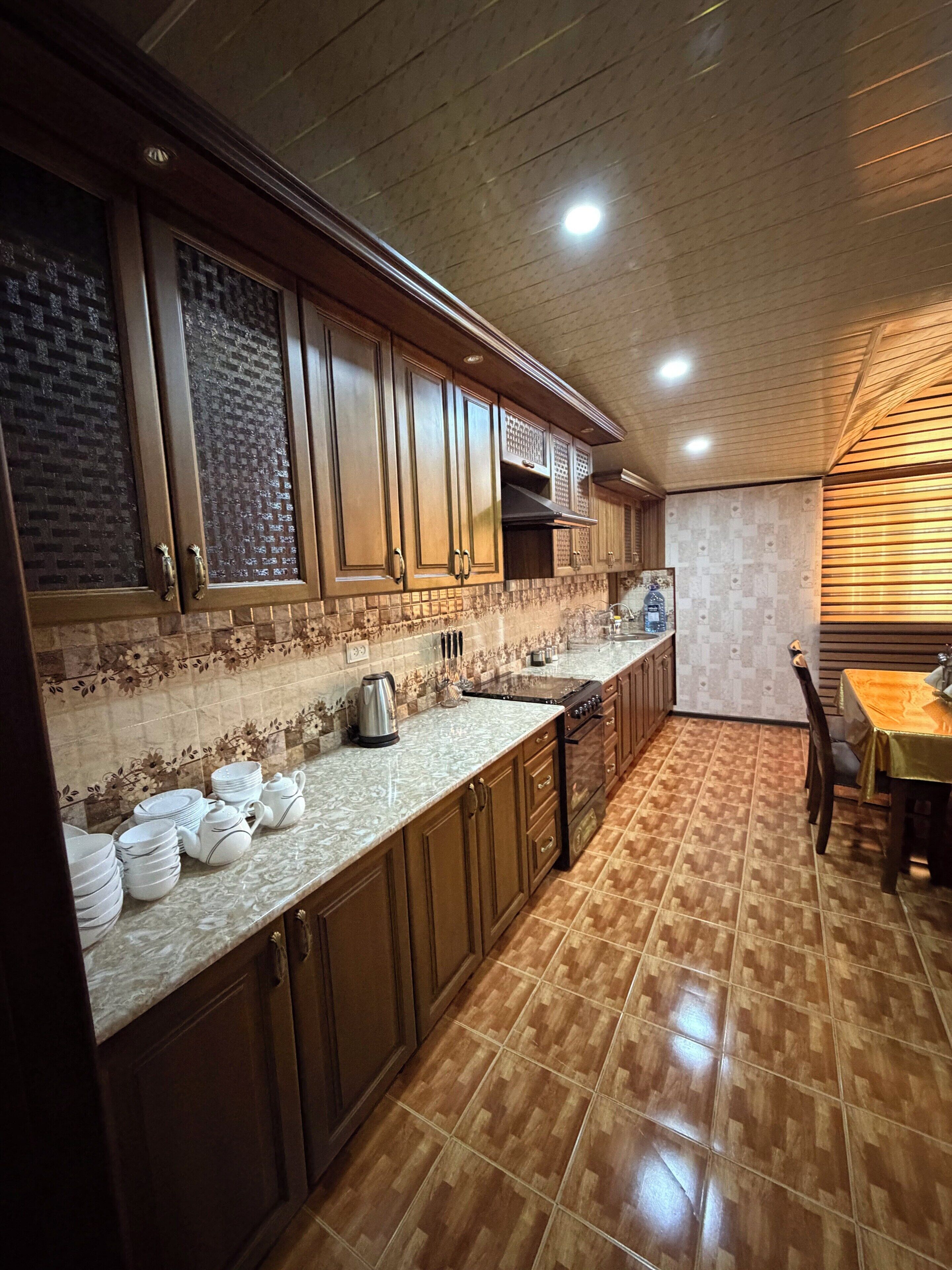 A kitchen with wooden cabinets, a tiled backsplash, and a dining area with a table and chairs.