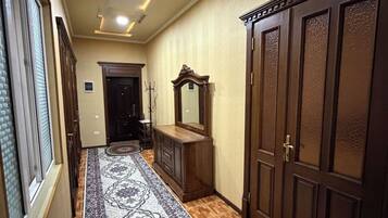 A hallway with a patterned carpet, wooden wardrobe, and a mirror.