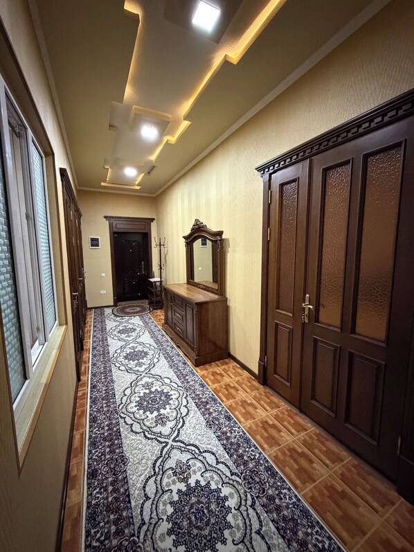 A hallway with a patterned carpet, wooden wardrobe, and a mirror.