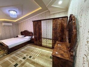 A bedroom with a bed, wardrobe, vanity, and a ceiling light fixture.