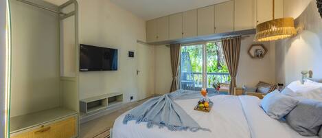 A bedroom with a bed, a TV, a ceiling fan, and a window with curtains.