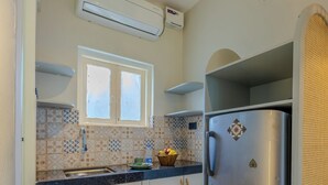 Et kompakt køkken med et rustfrit stålkøleskab, et vindue over vasken og et flisebeklædt backsplash.