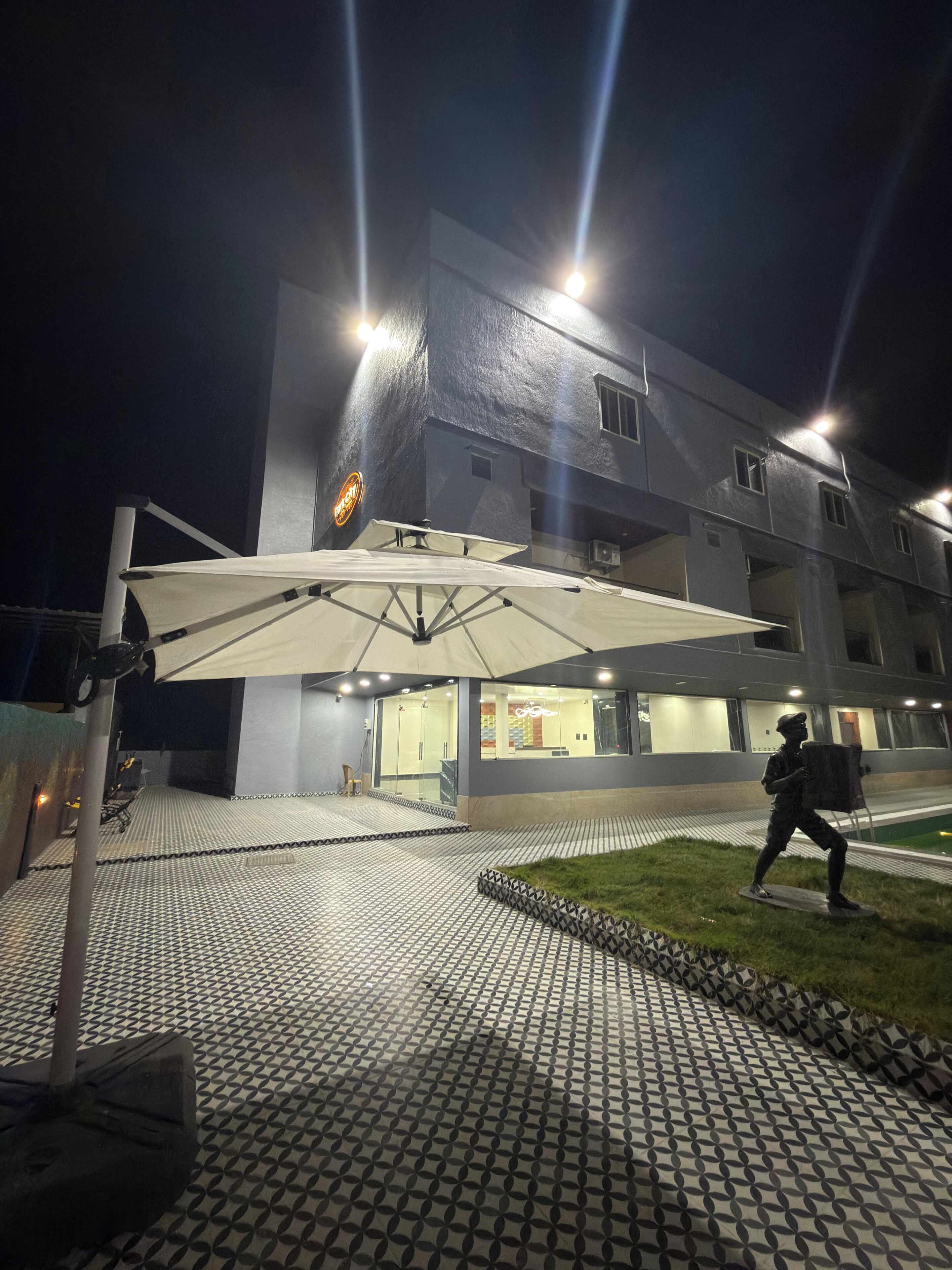 Um edifício com área de estar coberta ao ar livre, uma estátua e um pavimento estampado.