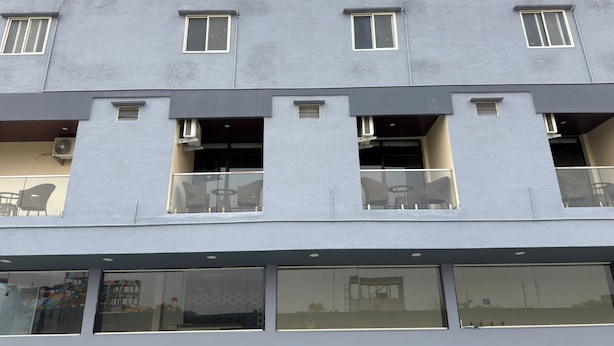 Um edifício com várias varandas, cada uma com guarda-corpos de vidro e cadeiras.