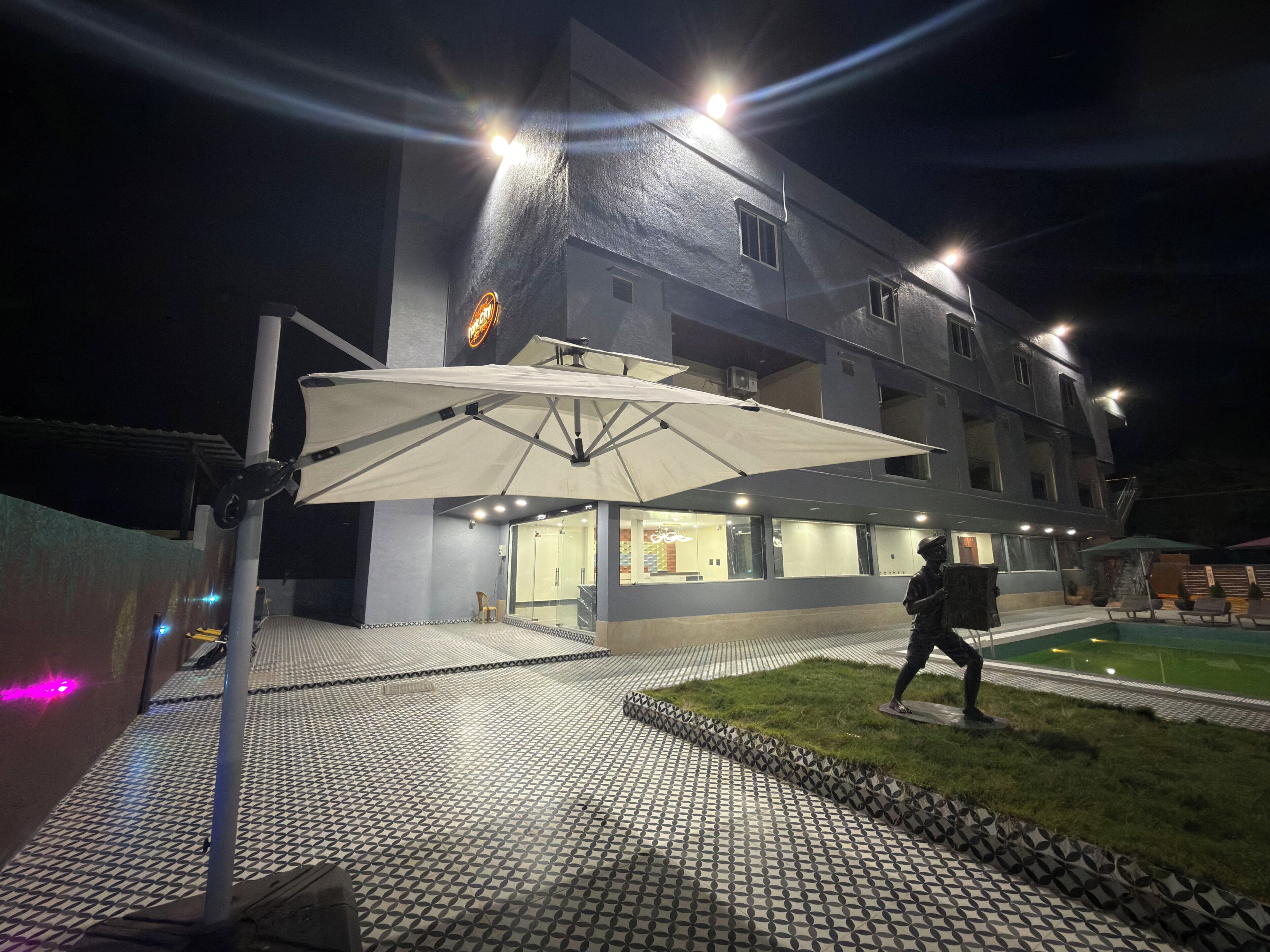 A building with a tiled entrance, a covered outdoor seating area, and a person walking.