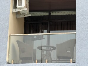 A balcony with wicker furniture and a glass partition. - PARK CITY HOTEL (Vallur)