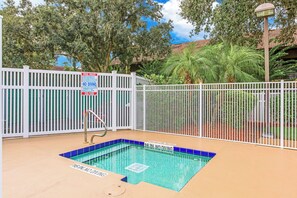 A pool with a 16-inch no diving sign, surrounded by a white fence, and trees in the background. - Sunshine, Stretch Out, Repeat 1 BR Suite (Kissimmee)